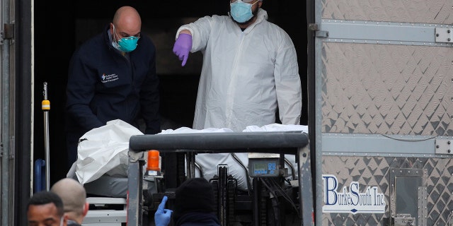 Health workers load a deceased person into a trailer outside of the Brooklyn Hospital Center, during the coronavirus disease (COVID-19) outbreak, in the Brooklyn borough of New York City, New York, U.S., March 30, 2020. REUTERS/Brendan McDermid - RC2MUF91UUBG