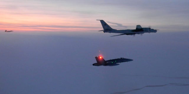 In this March 9, 2020 photo released by the North American Aerospace Defense Command (NORAD), a Russian Tu-142 maritime reconnaissance aircraft, top right, is intercepted near the Alaska coastline. 