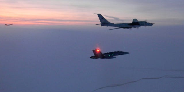 A Russian Tu-142 maritime reconnaissance aircraft, top, is intercepted near the Alaska coastline In this March 9, 2020, photo.