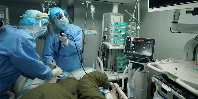 In this March 17, 2020 photo released by China's Xinhua News Agency, medical workers use a bronchoscope to treat a coronavirus patient at the Huoshenshan field hospital in Wuhan in central China's Hubei Province. Last month, Wuhan was overwhelmed with thousands of new cases of coronavirus each day.