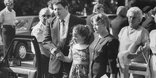 Todd and Diana Moore, parents of murder victim Michael Moore, with 9-yr-old daughter Dawn walking outside the Holy Cross Episcopal Church at Michael's funeral.