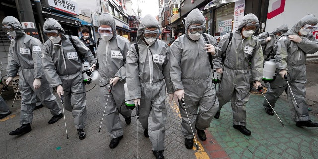 Army soldiers wearing protective suits spray disinfectant as a precaution against the new coronavirus at a shopping street in Seoul, South Korea, Wednesday, March 4, 2020. (AP Photo/Ahn Young-joon)
