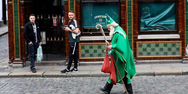 A man dressed as St Patrick walks past a closed bar in Dublin city center, Monday, March, 16, 2020.