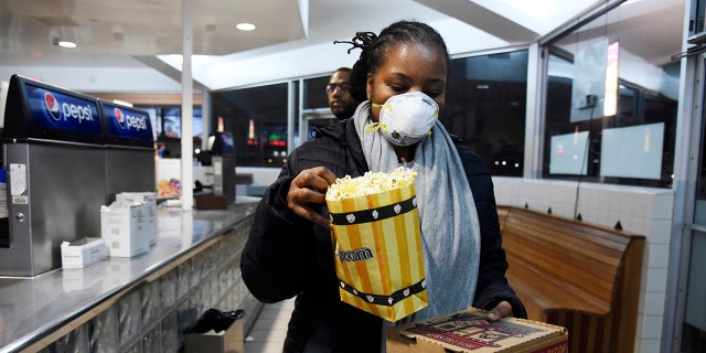 A California woman wears a mask as she collects her concessions at the Paramount Drive-In Theatres, Thursday, March 19, 2020, in Paramount, Calif. (AP Photo/Chris Pizzello)