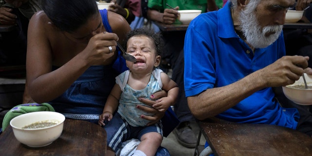Zoraida Silva, 26, feeds her six month baby Jhon Angel, at a soup kitchen in The Cemetery slum, in Caracas, Venezuela. Silva said that she can not afford to have 3 meals a day, and she has been eating at the soup kitchen for two years ago. According to a survey recently published by the U.N. World Food Program, one of every three Venezuelans cope with food insecurity, unable to get enough food to meet their basic dietary needs. (AP Photo/Ariana Cubillos)