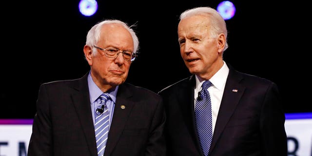 Presidential candidates Bernie Sanders and Joe Biden talk before a Democratic primary debate in Charleston, South Carolina, Feb. 25, 2020.
