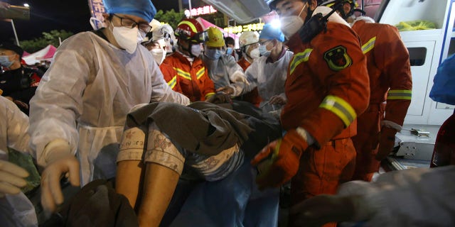 Rescuers carry a woman pulled from the rubble of a collapsed hotel to an ambulance after being trapped for 52 hours.