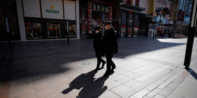 In this Tuesday, March 10, 2020, security guards patrolling the quiet Wangfujing shopping, a usually popular tourist spot before the new coronavirus outbreak in Beijing.