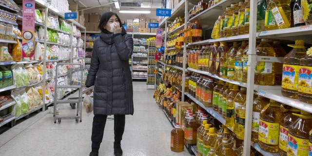 A shopper wearing a face mask browses an aisle of cooking oil in a supermarket in Beijing on Monday, March 16, 2020.