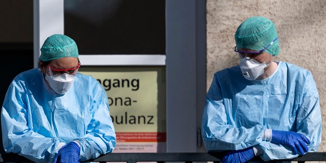 Employees of the Corona Outpatient Clinic at the University Hospital stand in protective clothing and breathing masks in front of the entrance in Dresden, Germany, on Wedneday. (Robert Michael/dpa via AP)