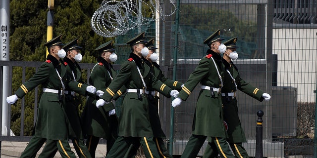Chinese paramilitary wearing masks march by during their duty in an embassy district in Beijing on Monday, March 16, 2020. With more imported cases of the new coronavirus, starting Monday, travelers arriving in Beijing from overseas will be quarantined for 14 days in designated facilities at their own expense. For most people, the new coronavirus causes only mild or moderate symptoms. For some it can cause more severe illness. (AP Photo/Ng Han Guan)