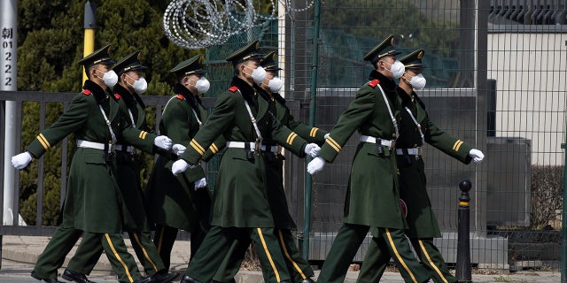 Chinese paramilitary wearing masks march by during their duty in an embassy district in Beijing on Monday, March 16, 2020. With more imported cases of the new coronavirus, starting Monday, travelers arriving in Beijing from overseas will be quarantined for 14 days in designated facilities at their own expense. For most people, the new coronavirus causes only mild or moderate symptoms. For some it can cause more severe illness. (AP Photo/Ng Han Guan)