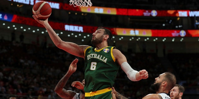 In this Sept.  15, 2019, file photo, Andrew Bogut of Australia puts up a shot over Amath M'Baye, left, and Evan Fournier of France during their third placing match for the FIBA ​​Basketball World Cup at the Cadillac Arena in Beijing.