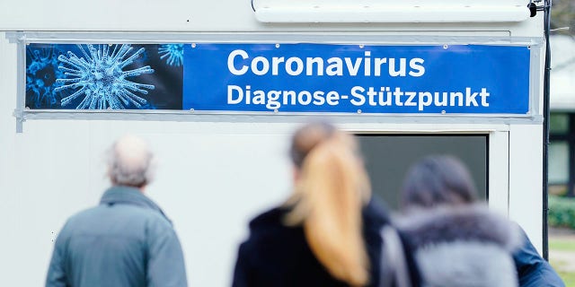 People stand in front of containers with a banner reading "Coronavirus Diagnosis Base" on the grounds of the University Hospital in Mannheim, Germany, on Wednesday. (Uwe Anspach/dpa via AP)