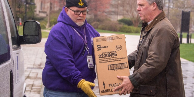 The Very Rev. Randolph Marshall Hollerith, dean of Washington National Cathedral, on the right, helps load boxes of masks to be taken to local hospitals.