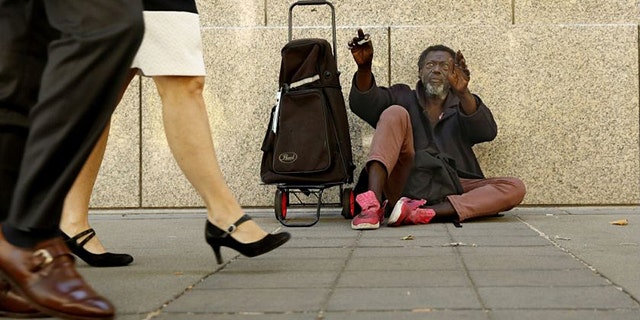 Carl Wallace, who says he is homeless and lives on the streets, waves to people passing by in Sacramento, Calif., Wednesday, June 26, 2019. New government data, released Wednesday show the number of people experiencing homelessness in Sacramento County has increased 19% over the last two years. (AP Photo/Rich Pedroncelli)