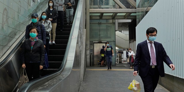 People wearing face masks walk at a downtown street in Hong Kong Monday, March 16, 2020.