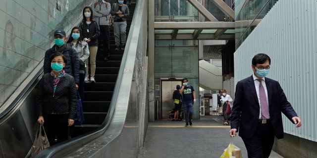 People wearing face masks walk at a downtown street in Hong Kong Monday, March 16, 2020.