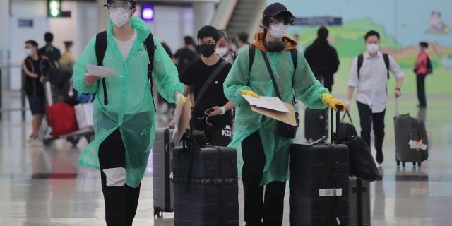 Passengers wear protective suits and face masks to protect themselves from possibly contracting the coronavirus after arriving at the Hong Kong airport, Monday, March 23, 2020.