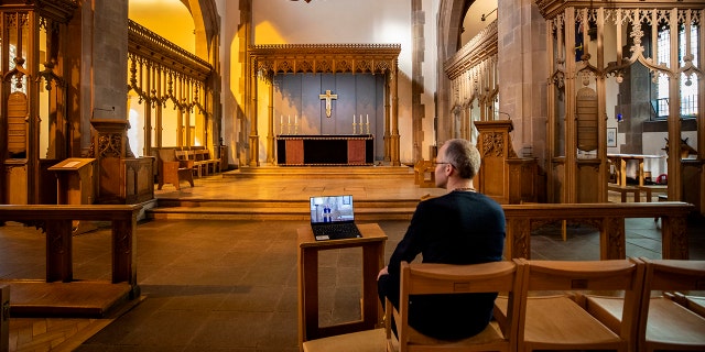 A church parishioner watches a laptop inside Liverpool Parish Church (Our Lady and St Nicholas) in Liverpool, England, during the Church of England's first virtual Sunday service given by the Archbishop of Canterbury Justin Welby. (Peter Byrne/PA via AP)