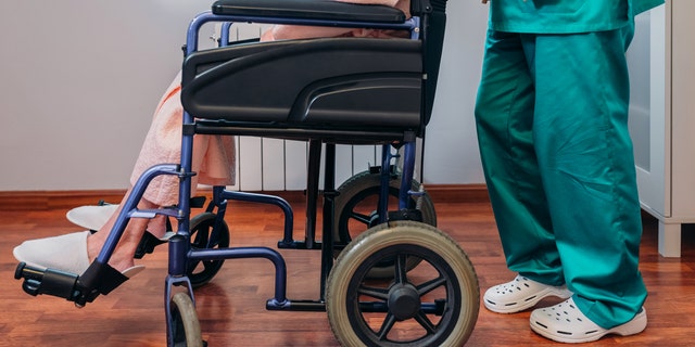 A female doctor carries an elderly patient in a wheelchair