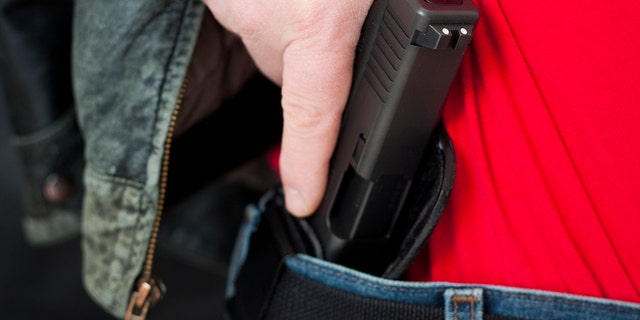 A man drawing his modern polymer (Glock) .45 caliber pistol from an IWB (inside the waistband) holster under his leather jacket.  Showing proper trigger control by keeping his finger off the trigger as he draws.