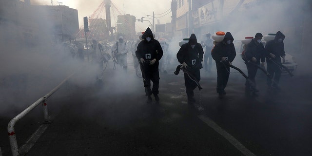 Firefighters disinfect a street against the new coronavirus in western Tehran on Friday. (AP Photo/Vahid Salemi)