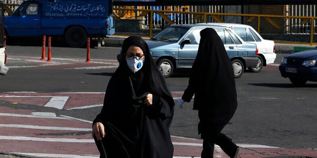 A woman wearing a face mask crosses an intersection in northern Tehran, Iran, Wednesday, March 4, 2020. With deaths spiking in Iran and Italy and infections spreading quickly through Europe, the Mideast and the Americas, countries were considering new drastic measures to curb the new coronavirus that first emerged in China.
