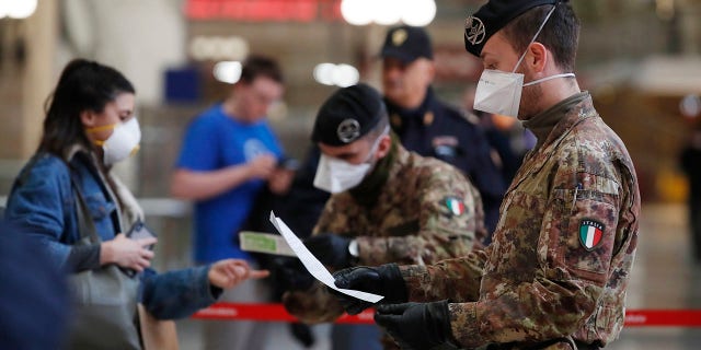 Police officers and soldiers check passengers leaving from Milan main train station, Italy, Monday, March 9, 2020. (AP Photo/Antonio Calanni)