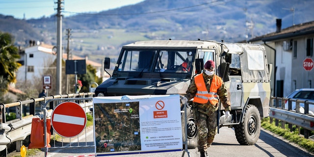 An Italian army soldier blocks off a road leading to the village of Vo'Euganeo, in Italy's northern Veneto region, on Friday, Feb. 28, 2020.