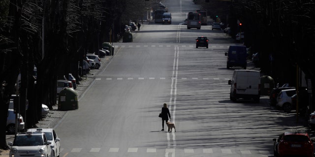 A woman walks her dog in the EUR neighborhood in Rome, Monday, March 23, 2020.