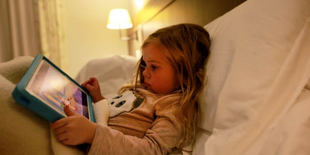 Here, a three-year-old girl is glued to an iPad in a hotel room during a vacation. (Photo by Tim Clayton/Corbis via Getty Images)