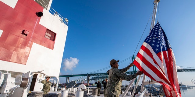 Logistics Specialist 1st Class Tavares Littleton, from Chicago, raises the American flag during morning colors aboard the hospital ship USNS Mercy on Sunday in Los Angeles.