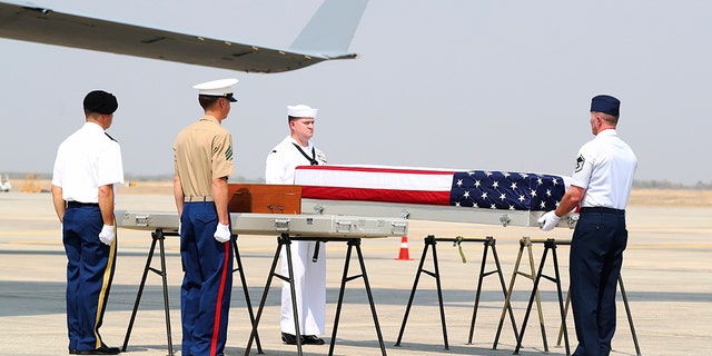 U.S. military guard of honor prepare to carry a coffin covered with U.S. national flag during repatriation ceremony at Mandalay International Airport Thursday, in Mandalay, central Myanmar. The U.S. military has repatriated what may be the remains of service personnel who were lost in action in Myanmar during World War II. (AP Photo/Thein Zaw)