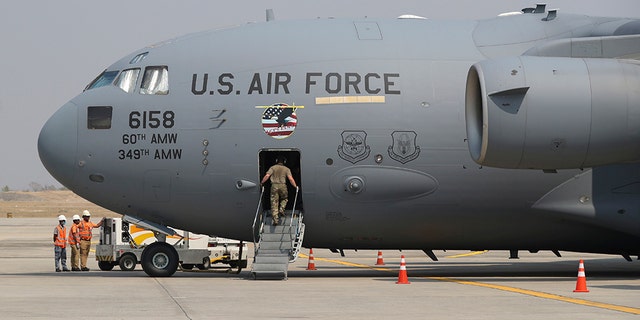 A staff gets on U.S. Air Force plane at Mandalay international airport during a repatriation ceremony Thursday, March 12, 2020, in Mandalay, central Myanmar. (AP Photo/Thein Zaw)