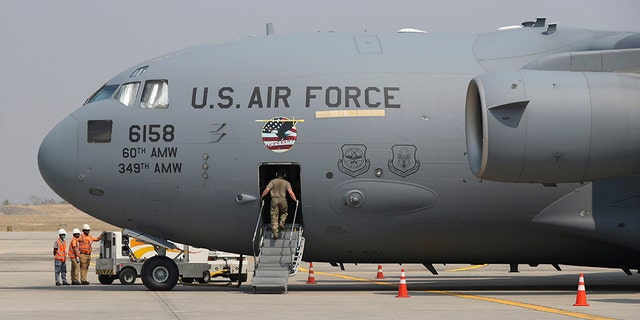 A staff gets on U.S. Air Force plane at Mandalay international airport during a repatriation ceremony Thursday, March 12, 2020, in Mandalay, central Myanmar. (AP Photo/Thein Zaw)