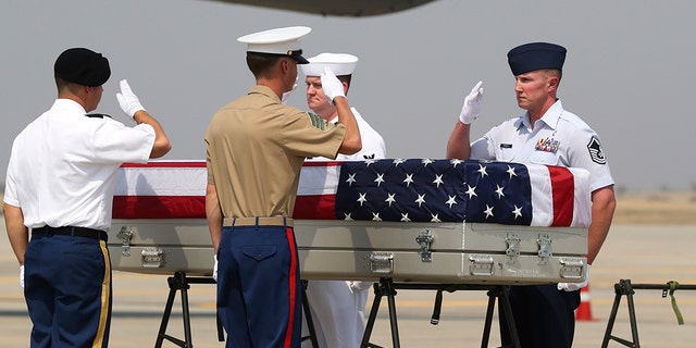 U.S. military guard of honor salute a coffin covered with U.S. national flag during a repatriation ceremony at Mandalay International Airport Thursday, March 12, 2020, in Mandalay, central Myanmar. (AP Photo/Thein Zaw)