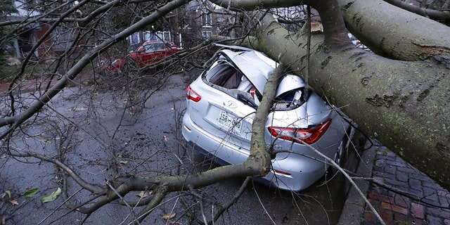 A car crushed by a tree sits on a street after a tornado touched down Tuesday, March 3, 2020, in Nashville, Tenn.