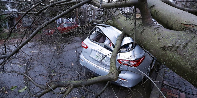 A car crushed by a tree sits on a street after a tornado touched down Tuesday, March 3, 2020, in Nashville, Tenn.