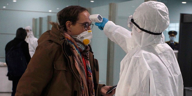 A passenger wearing a mask as a precaution against a new coronavirus has his temperature checked before boarding a flight to Vladivostok, Russia, at the Pyongyang International Airport in Pyongyang, North Korea, Monday, March 9, 2020. (AP Photo/Cha Song Ho)