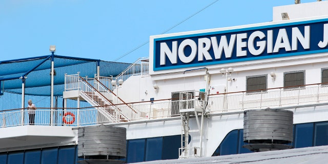 A woman, bottom left, looks out from the Norwegian Jewel cruise ship in Honolulu on March 22. (AP Photo/Caleb Jones)