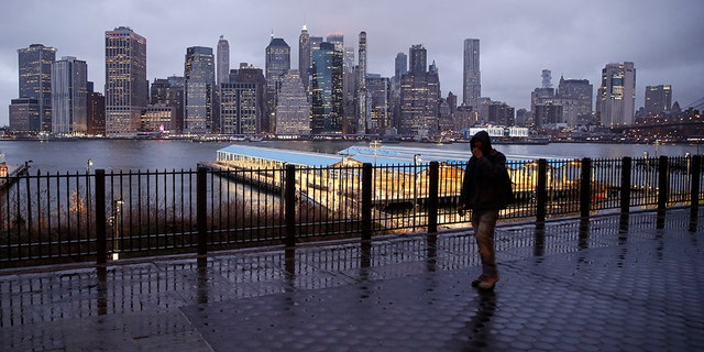 A person walks on an empty sidewalk across from the Manhattan skyline on Tuesday. (AP Photo/John Minchillo)