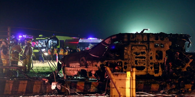 Firemen and rescuers talk beside the remains of a Lion Air, West Wind 24 aircraft after it caught fire during takeoff at Manila's International Airport in the Philippines on Sunday, March 29, 2020.