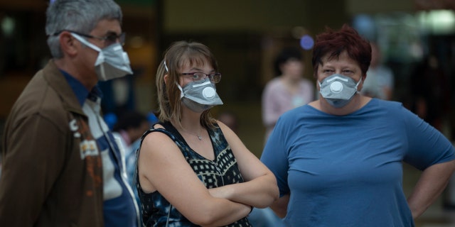 People wearing masks wait for passengers at Johannesburg's O.R. Tambo International Airport, Monday, March 16, 2020 a day after President Cyril Ramaphosa declared a national state of disaster.