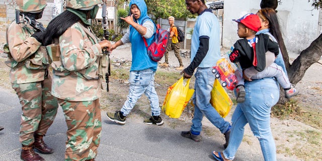 Soldiers interact with resident while on patrol in Mannenburg, Cape Town, South Africa on Saturday. (AP Photo)