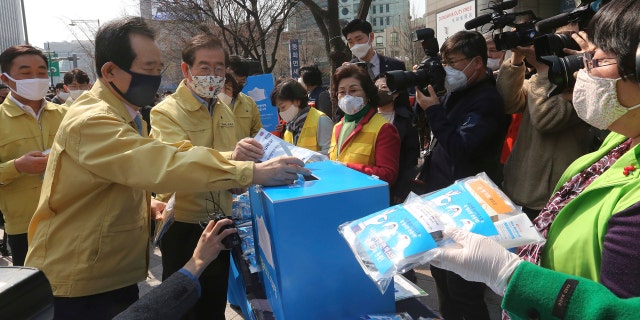 South Korean Prime Minister Chung Se-kyun, second from left, puts an envelope containing a face mask into a charity box during a campaign for the donation of face masks to impoverished people amid the spread of the new coronavirus in Seoul, South Korea.