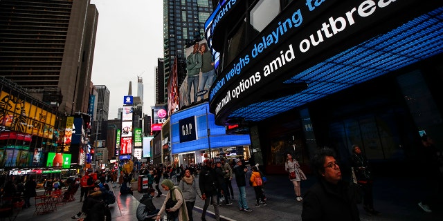 Pedestrians pass under a news ticker in Times Square, Wednesday, March 11, 2020, in New York, N.Y. The number of coronavirus cases in New York state jumped Sunday to more than 100, a spread that forced the suspension of classes at schools across the state, including a district that has a faculty member with a positive test and Columbia and Hofstra universities. For most people, the new coronavirus causes only mild or moderate symptoms. For some it can cause more severe illness.