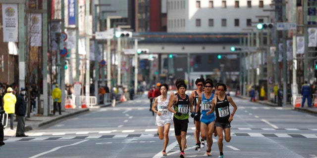 Runners race through the commercial district with less spectators at the Tokyo Marathon in Tokyo, Sunday, March 1, 2020.