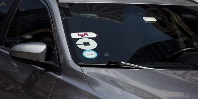 Lyft and Uber logos are seen on the windshield of a vehicle in New York on Aug. 9, 2018. (John Taggart/Bloomberg via Getty Images)
