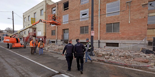 Police officers walk past rubble after an earthquake Wednesday, March 18, 2020, in Salt Lake City.